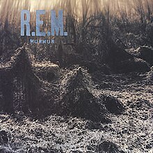 A train trestle covered in thick kudzu with R.E.M. / MURMUR written in blue